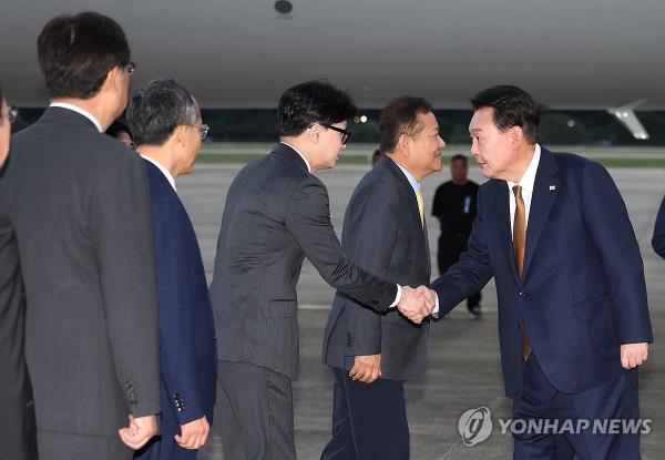 President Yoon Suk Yeol (R) shakes hands with ruling People Power Party chief Han Dong-hoon (3rd from L) at Seoul Air base in Seongnam, just south of Seoul, on Sept. 22, 2024, as Yoon arrives in South Korea after a trip to the Czech Republic. (Yonhap)